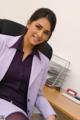 A woman in a purple suit sitting at a desk.