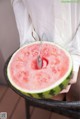 A person holding a slice of watermelon with a spoon in it.