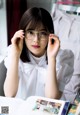 A woman wearing glasses sitting at a table with a book.