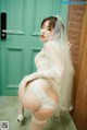 A woman in a wedding dress and stockings posing in front of a door.