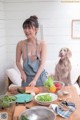 A woman in an apron preparing food with a dog in the background.