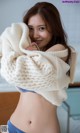 A woman in a white sweater and blue panties posing for a picture.