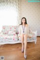 A woman sitting on a white couch in a room.