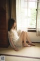 A woman sitting on the floor in front of a window.