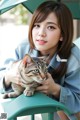 A woman sitting on a green chair holding a cat.