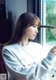 A woman looking out of a window with her hand on the window sill.