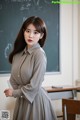 A woman standing in front of a blackboard in a classroom.