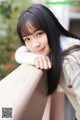 A young woman leaning on a railing with her hand on her chin.