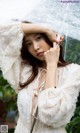 A woman in a white dress holding an umbrella.