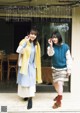 Two young women standing next to each other in front of a building.