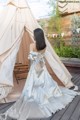 A woman in a wedding dress sitting in front of a teepee.