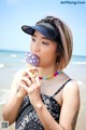 A woman eating an ice cream cone on the beach.