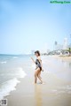 A woman in a bathing suit walking on the beach.