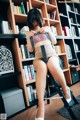 A woman sitting on a chair in front of a bookshelf.